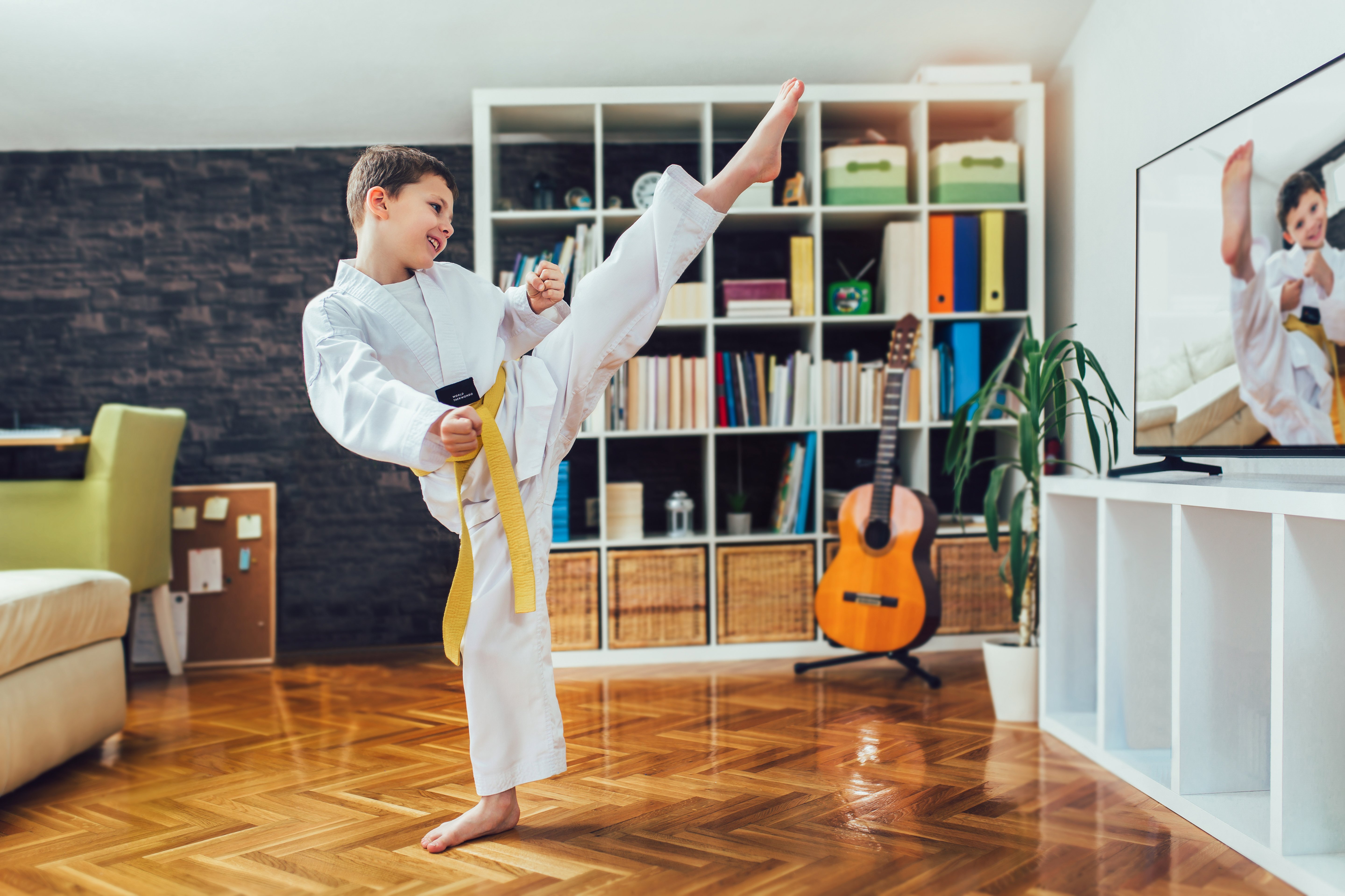 Student practicing kicks in a living room at home