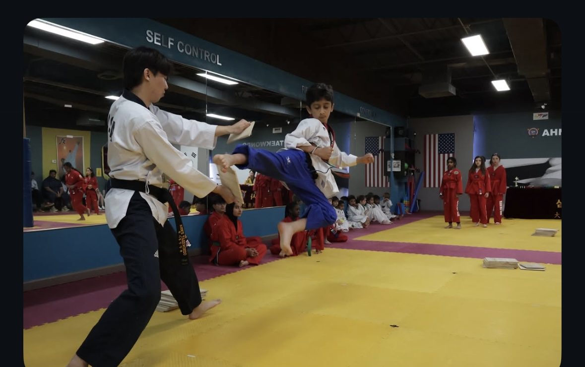 Young student performing a flying board break at Ahn's Taekwondo