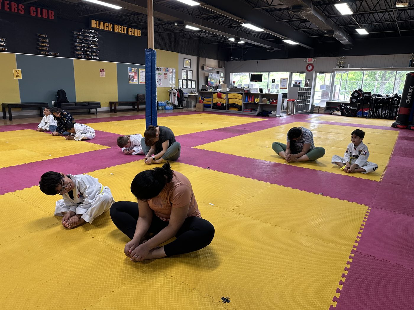 Parents and children warming up on the mat before training