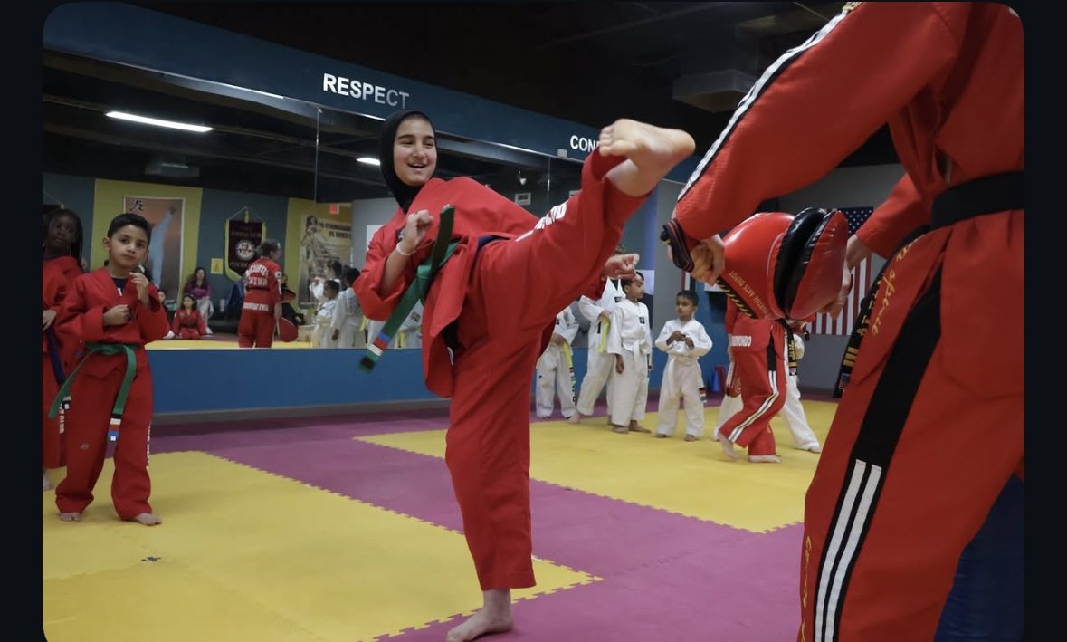 Student practicing kicks on a target pad with an instructor