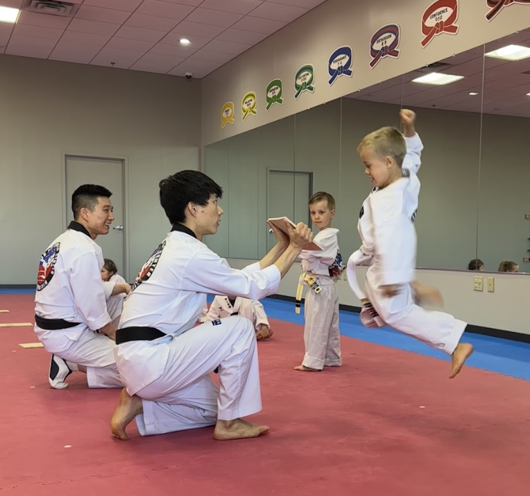 Instructors guiding a student through a jumping kick