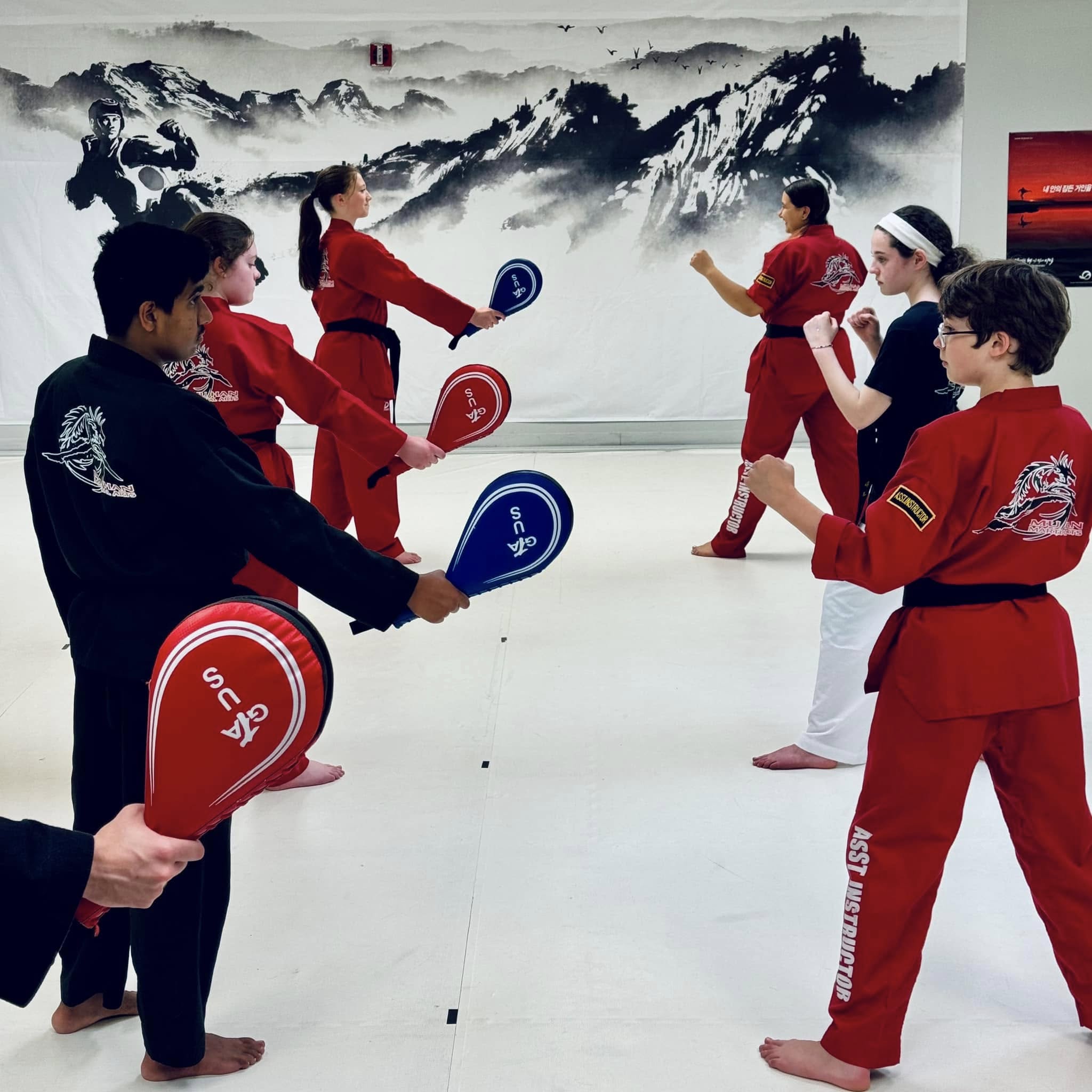 Junior students practicing kick pad drills with partners at Mu Han dojang
