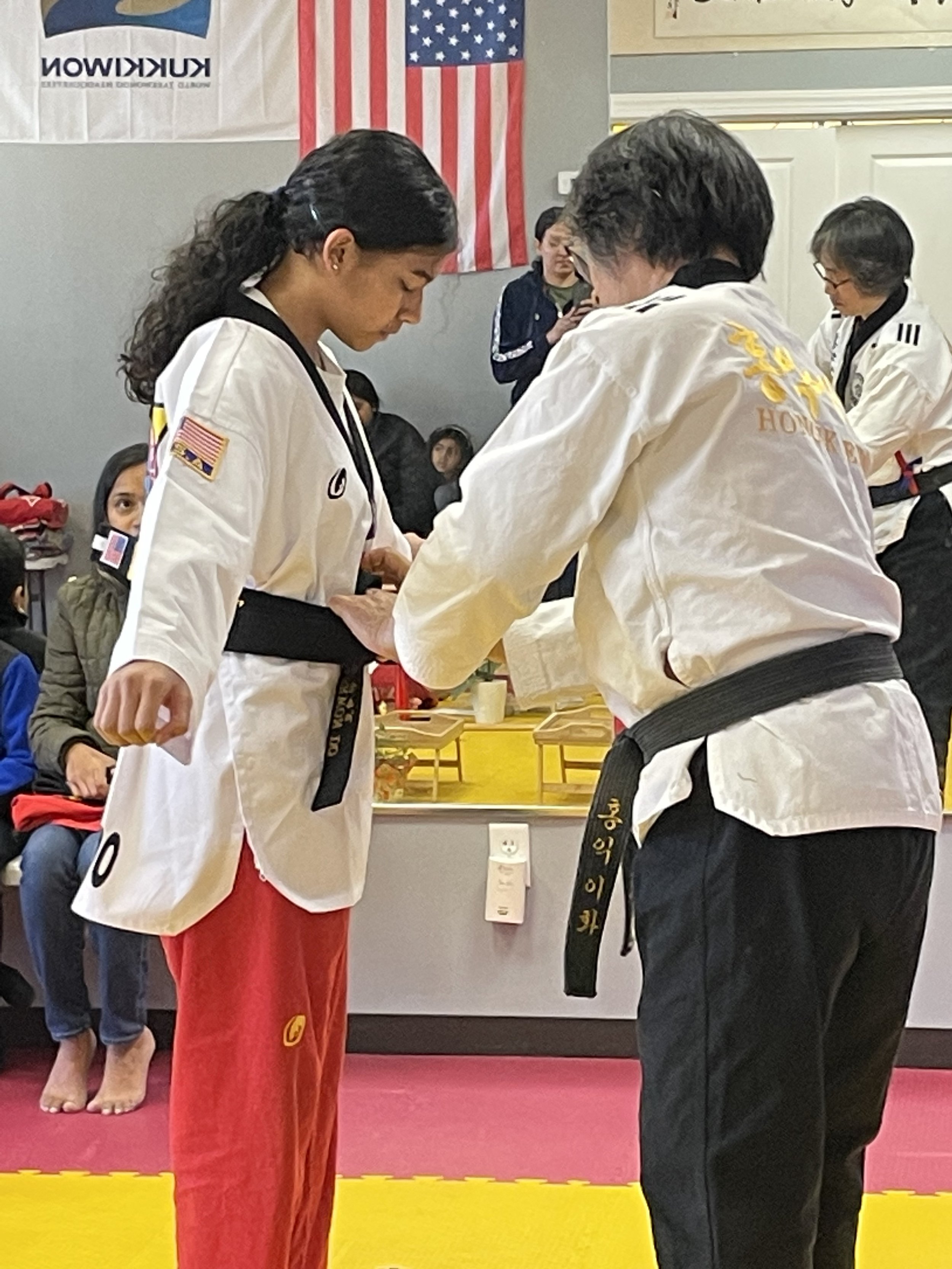 Instructor tying a new belt on a student during a promotion ceremony