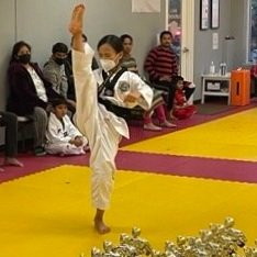 Black belt student performing a high kick during poomsae practice