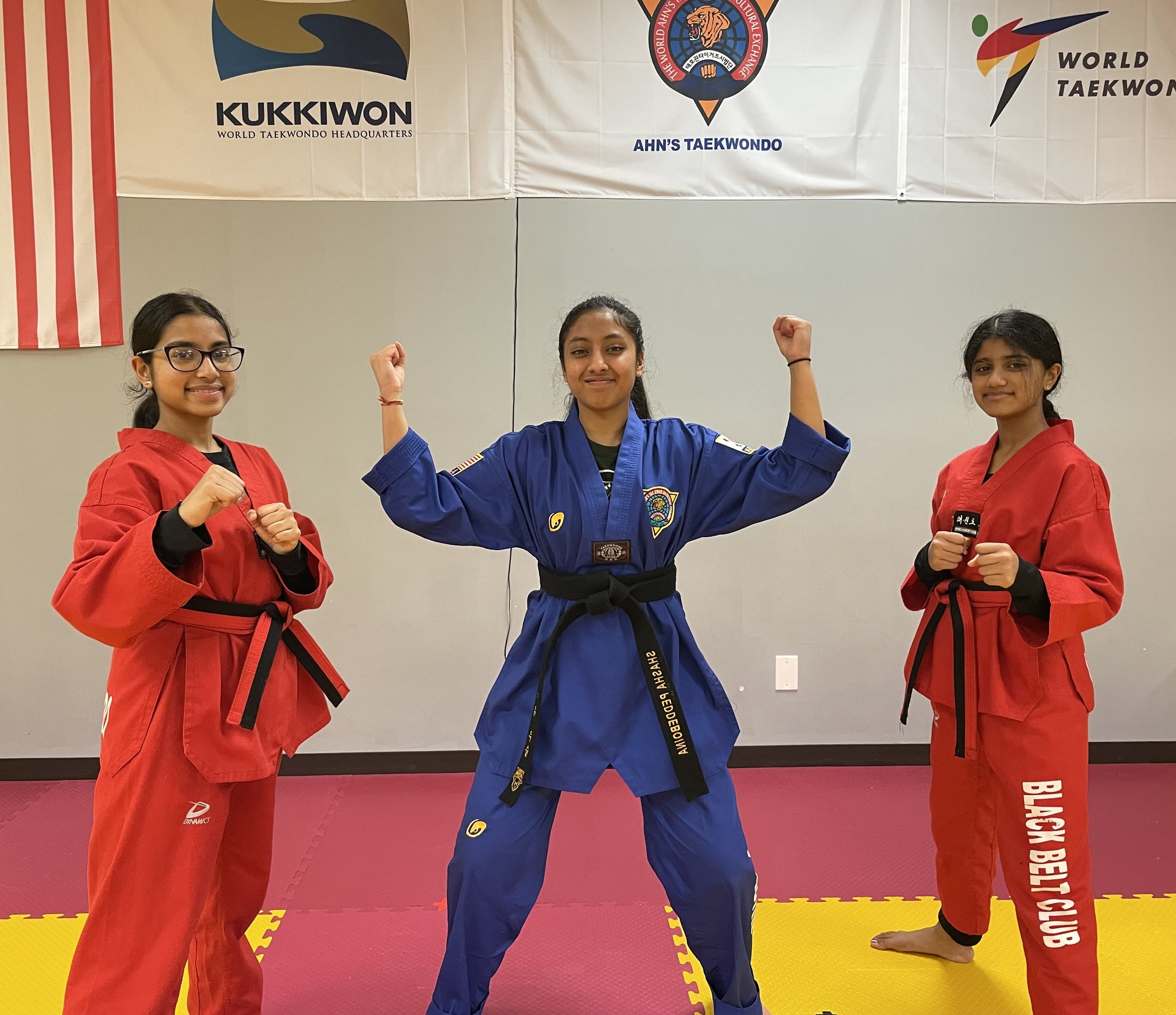 Black belt students in front of the Kukkiwon and World Taekwondo banners