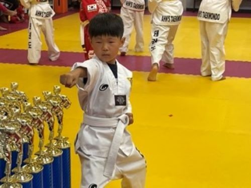 Student holding a championship trophy at a Taekwondo tournament