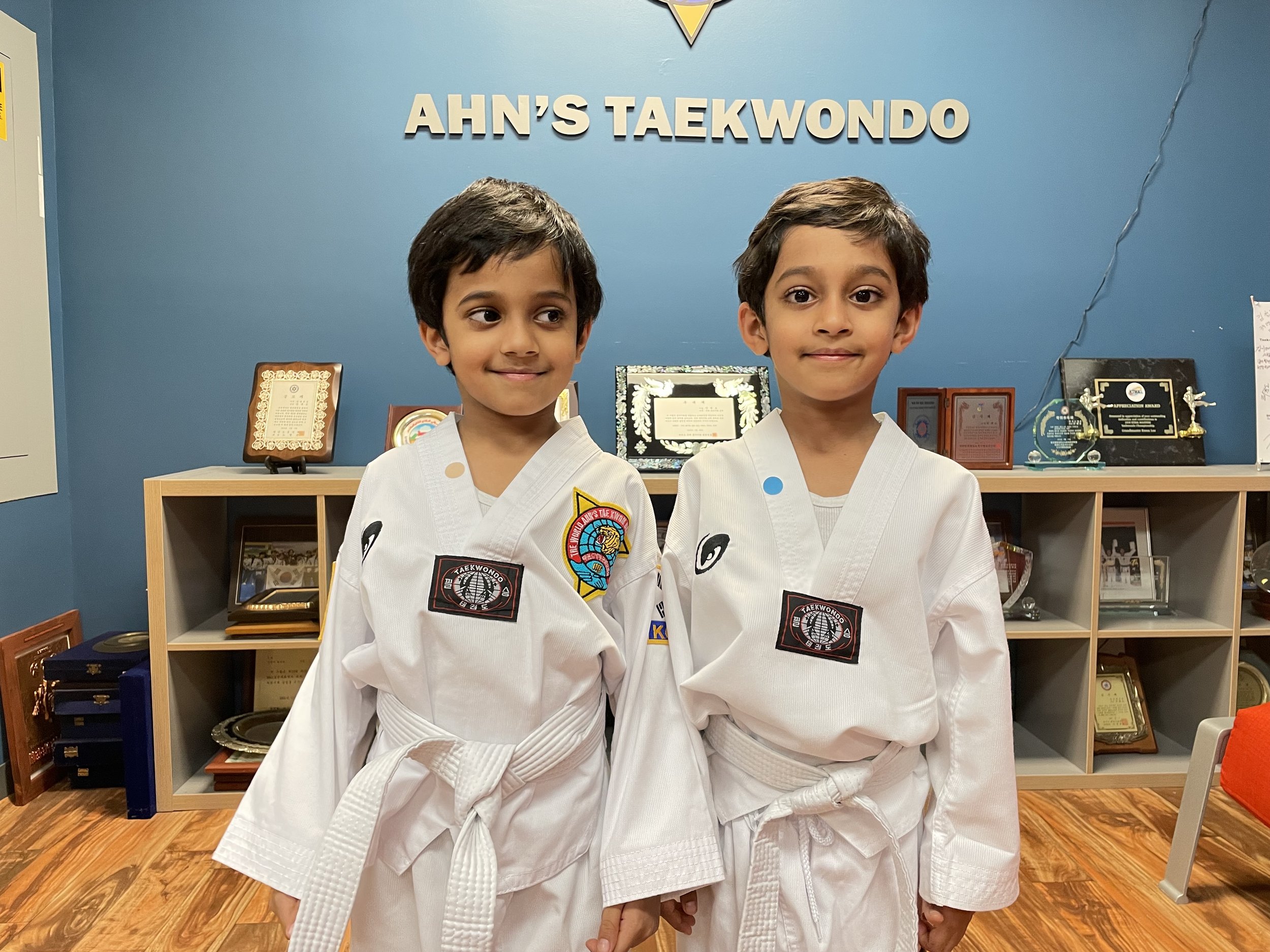 Two young students in front of the Ahn's Taekwondo wall sign