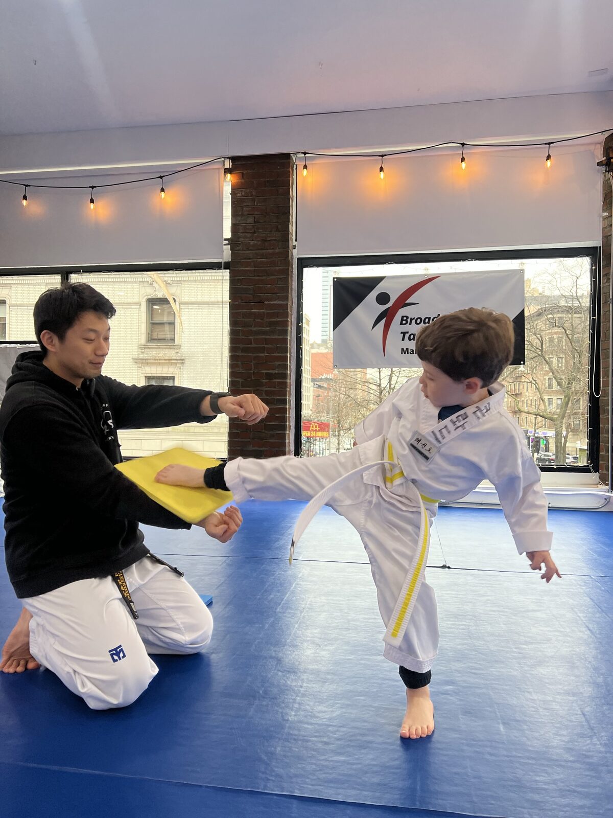 Instructor guiding a young student through a kick